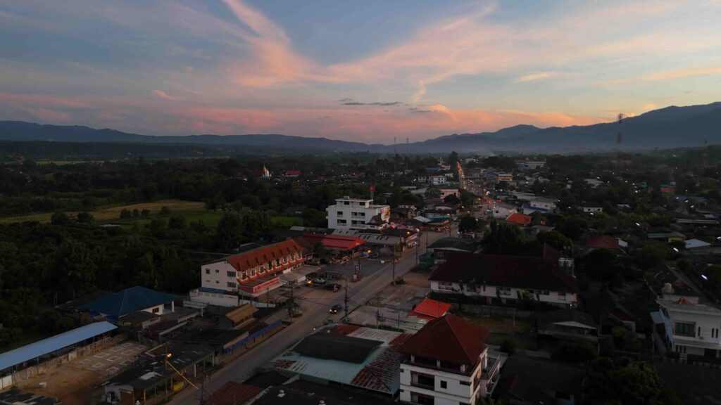 5 Great reasons to choose Chiang Mai Sunset over Chiang Dao with street lights illuminating the scene and a stunning mountain backdrop.