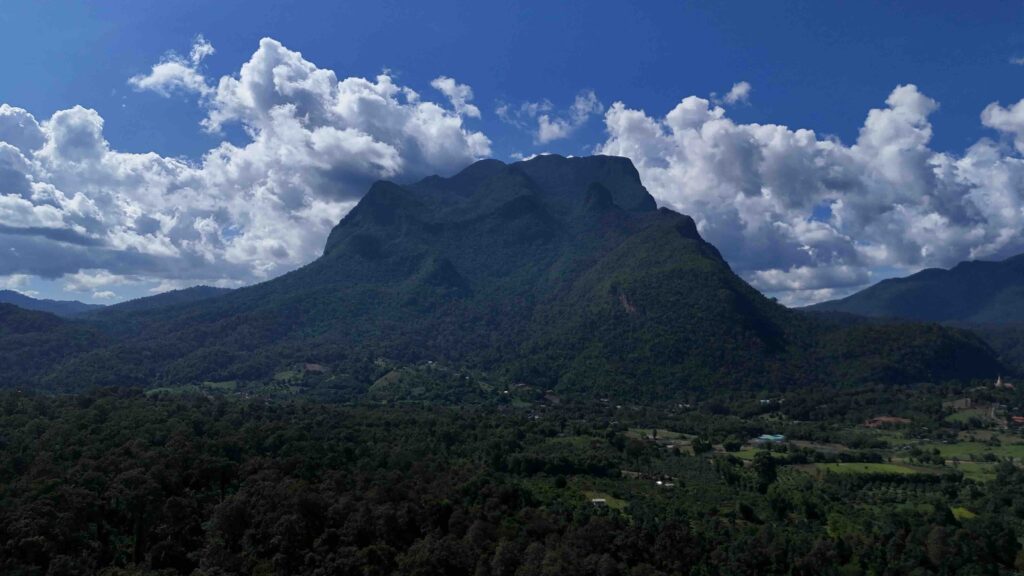 Day trip to Rice Fields under Doi Chiang Dao on a sunny day with fluffy clouds. Perfect for exploring nature!