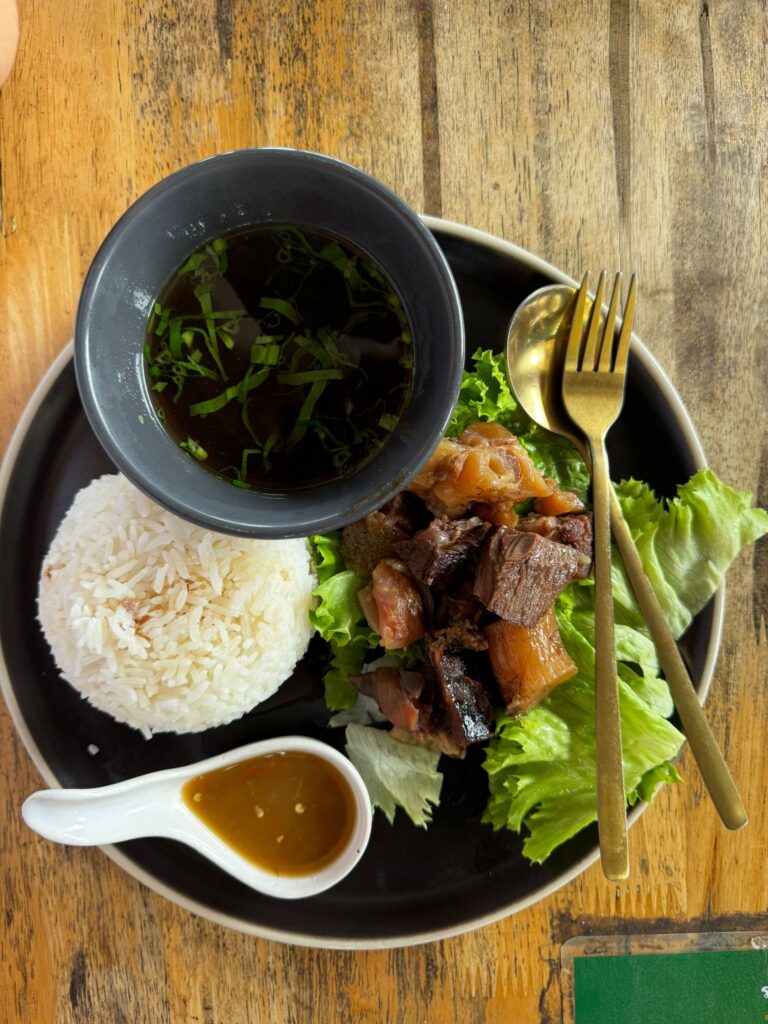 A hearty beef stew with tender beef cubes and tendon, served with steamed rice and a light, flavorful soup on the side