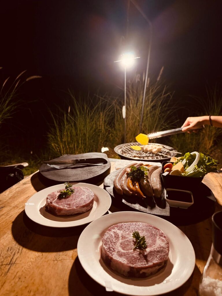 camping vibe with a charcoal grill sizzling thick-cut pork collar, creating a delicious and laid-back dinner experience