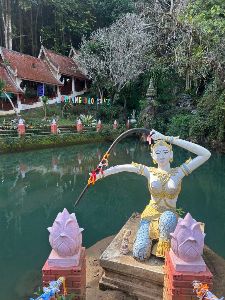 ntrance to Wat Tham Chiang Dao with temple structures nestled below limestone cliffs and lush greenery