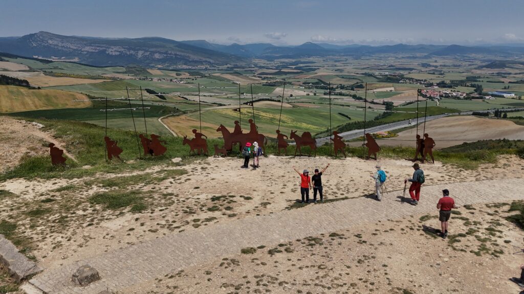 Pilgrims standing at the bronze statues on Alto de Perdón, captured by drone on the Camino de Santiago