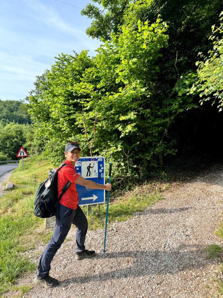 ilgrim next to a Camino de Santiago trail marker between Roncesvalles and Zubiri